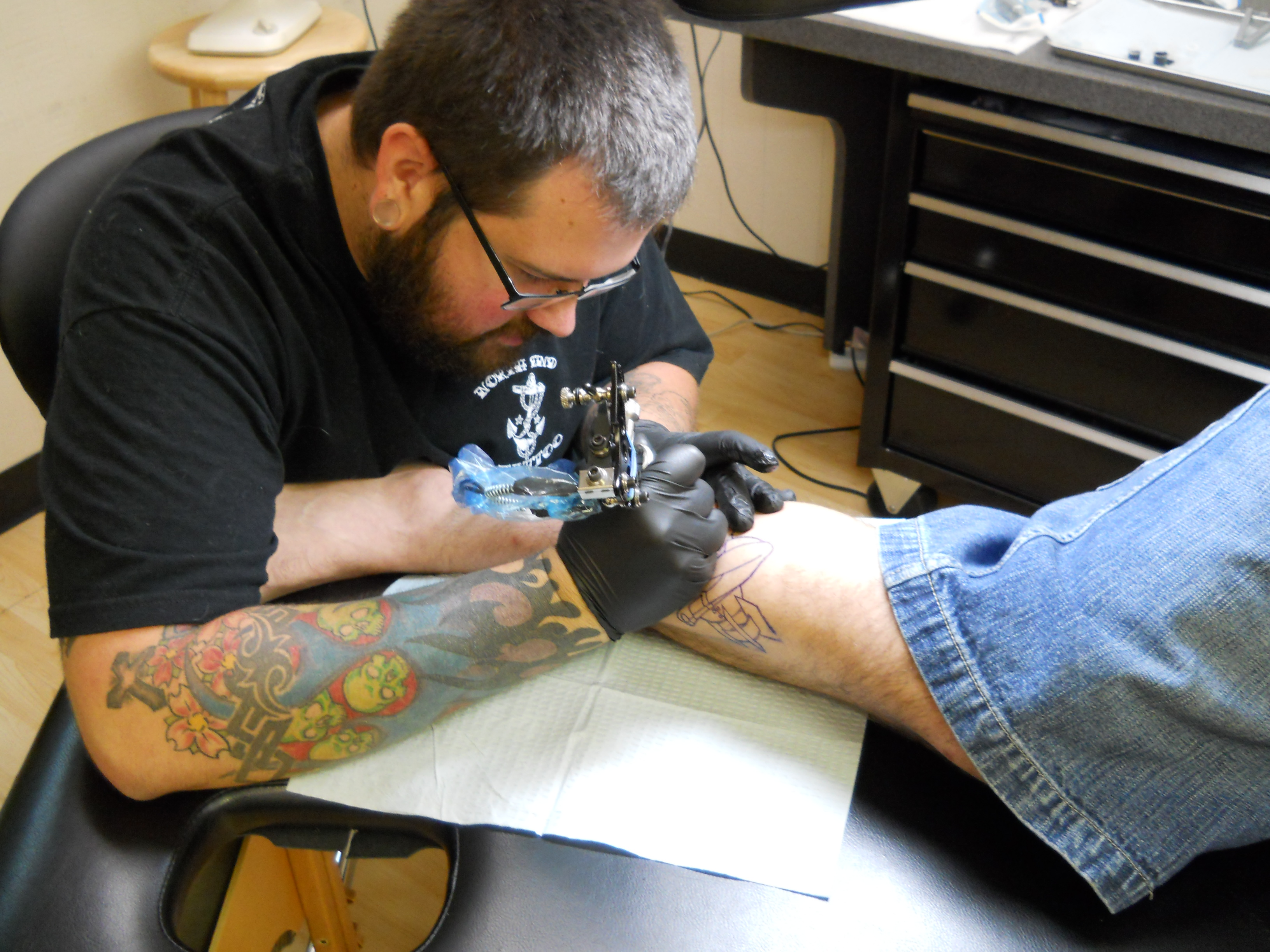 Chris tattooing on a customers calf muscle